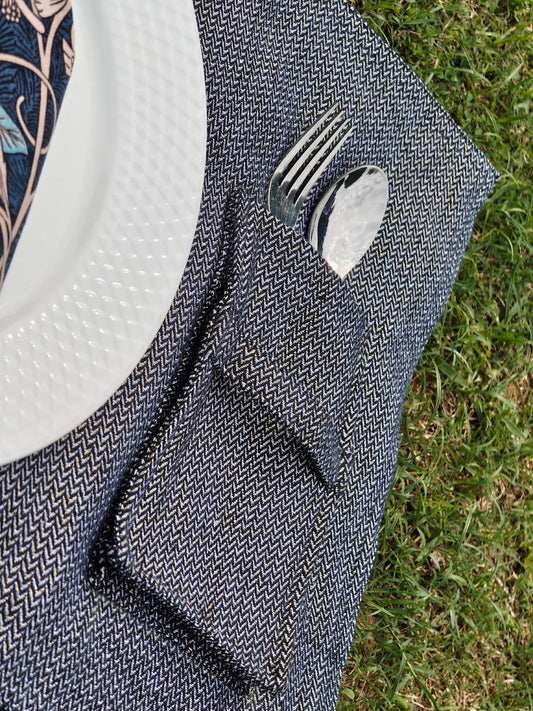 Blue woven placemat with cutlery pocket and a plate on grass