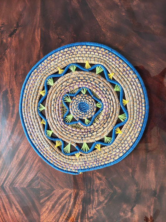 Decorative woven mat with blue and yellow patterns on a wooden surface